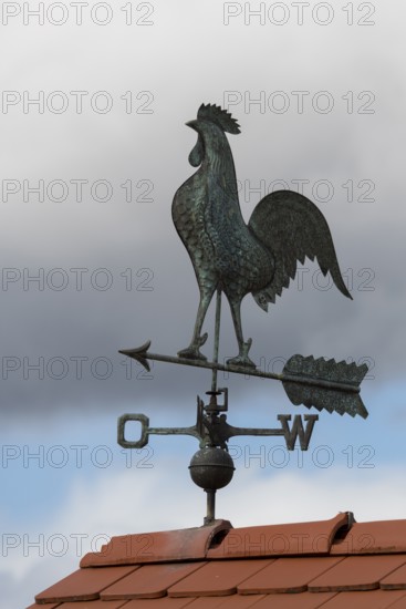 Metal weather vane with rooster on a tiled roof, blue sky and clouds, Baden-Württemberg, Germany