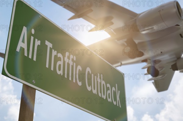 Air traffic cutback green road sign with airplane above