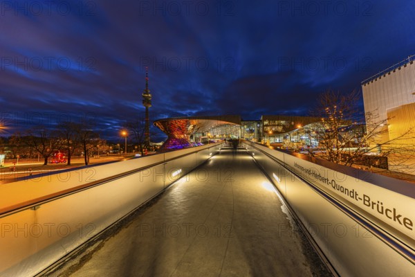 Evening atmosphere at BMW World, Johanna and Herbert Quandt bridge, in the back the TV tower in the Olympic Park, Petuelring, Munich, Upper Bavaria, Bavaria, Germany
