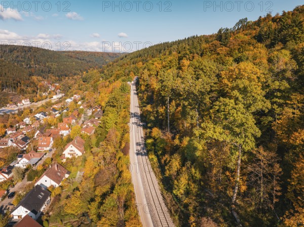 Village next to railroad tracks in autumn landscape with hills and forest, building of Hermann, Hesse, Bahn, Calw, Germany