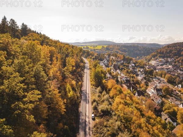 Autumn landscape with railway line through forest and village in hilly surroundings, building of Hermann, Hesse, railway, Calw, Germany