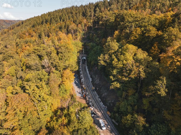 Railway tracks lead into a tunnel in autumn forest under a steeply rising hill, Bau der Hermann, Hesse, Bahn, Calw, Germany