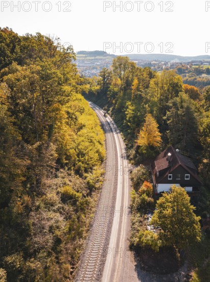 Railway line through autumnal forest with a small house and a gentle backdrop of hills, Bau der Hermann, Hesse, Bahn, Calw, Germany
