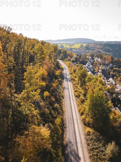Railway tracks run through autumn landscape and forest next to a village, aerial view, Hermann building, Hesse, railway, Calw, Germany