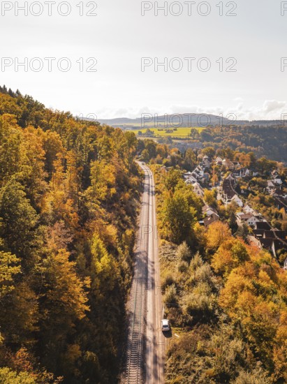 Panorama of a railway line through an autumnal forest next to a village and hills, building of Hermann, Hesse, Bahn, Calw, Germany