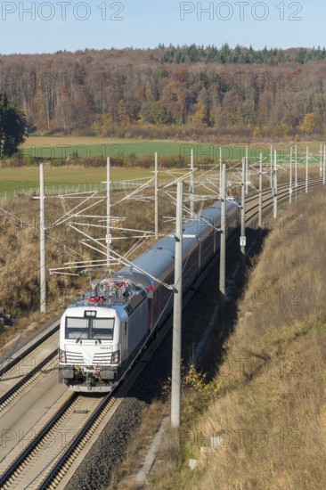 A passenger train travels through an autumnal landscape with fields and forests in the background, surrounded by overhead lines, new Stuttgart-Munich line, near Dornstadt, Swabian Jura, Baden-Württemberg, Germany