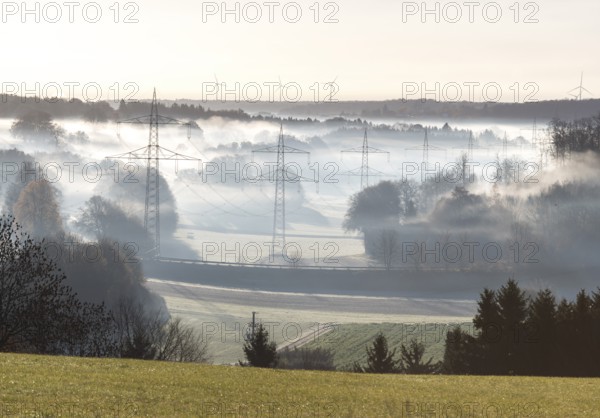 Landscape view with power poles and wind turbines in foggy morning light, Swabian Alps, Baden-Württemberg, Germany