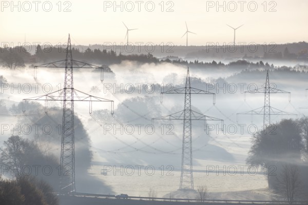 Foggy landscape with power poles and wind turbines at dawn, Swabian Jura, Baden-Württemberg, Germany