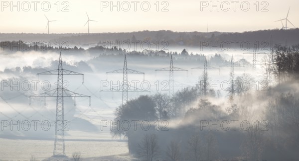 Foggy landscape with power poles and wind turbines in dawn light, Swabian Alb, Baden-Württemberg, Germany