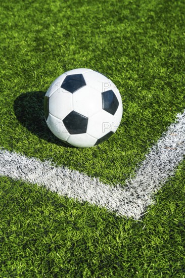 Soccer ball sits on the corner kick line of green artificial turf, ready for play symbolizing competition, teamwork, training, and the tense moment before a match kickoff