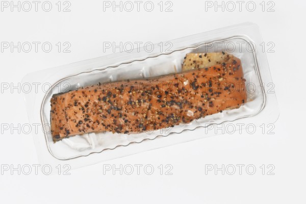 Smoked salmon fillet topped with pepper in plastic packaging for retail