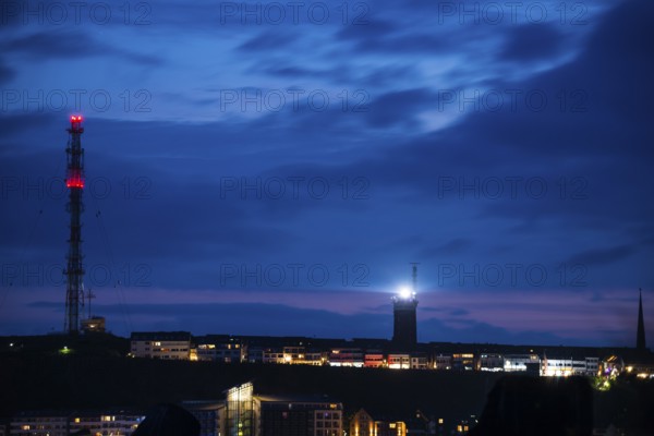 View of the highlands of the island of Heligoland at night with red-lit radio tower, radio tower, transmitter, bright lighthouse, dark church tower and deep blue sky with lots of clouds above, nighttime lowland in front of it, remnant of sunset in the night sky, quiet and dark atmosphere, cloud bank, weather, summer, night shot, long exposure, beacon, maritime, North Sea, Heligoland island, Pinneberg District, Schleswig-Holstein, Germany