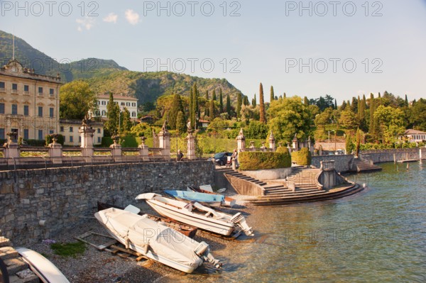 Waterfront with old villa, beautiful plants, trees and boats on Lake Como, Italian Lago di Como, one of the Upper Italian lakes, Lombardy region, Italy