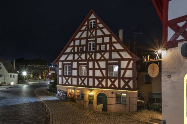 Night view of the historic half-timbered house, on the right the nose sign of a tailor shop, Lauf an der Pegnitz, Middle Franconia, Bavaria, Germany