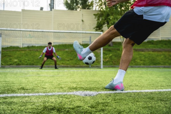 Soccer player preparing to kick a penalty shot towards the goal, with a vigilant goalkeeper in position, highlighting sports competition and the crucial moment of scoring