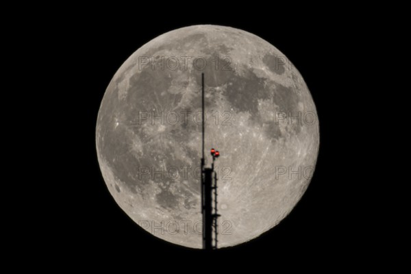 The full moon passes through the antenna on the roof of the European Central Bank (ECB), Frankfurt am Main, Hesse, Germany