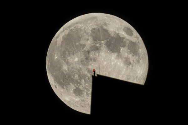 The full moon sweeps along the Frankfurt evening sky and passes the tip of the European Central Bank (ECB), making it look like a huge video game Pacman figure to the viewer, Frankfurt am Main, Hesse, Germany