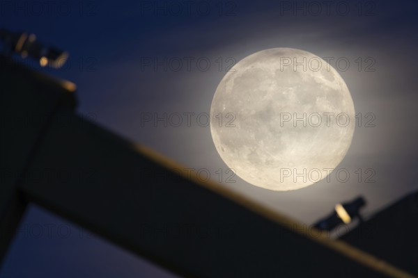 The full moon sweeps along the Frankfurt evening sky and passes the pillars of the rafter bridge, Frankfurt am Main, Hesse, Germany