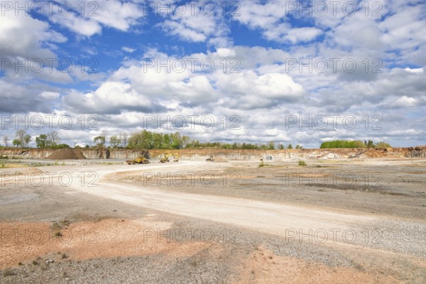 View in a limestone quarry with heavy machinery by a gravel road on a sunny summer day