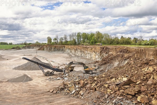 Excavator at a stone crusher with a conveyor in a quarry in a the countryside