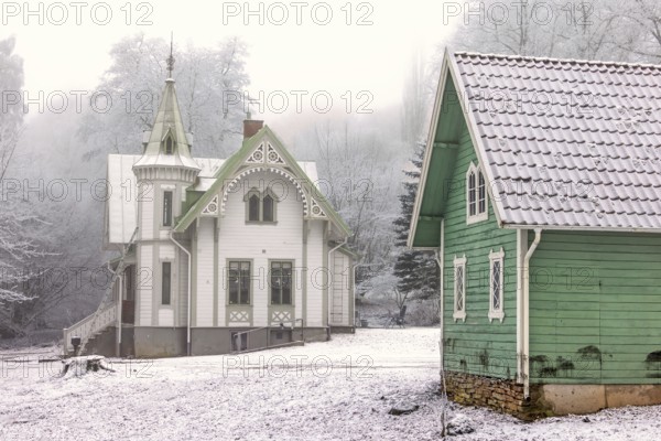 Idyllic old wooden house with beautiful carpentry and a garden shed a frosty and snowy cold misty winter day, Falköping, Sweden