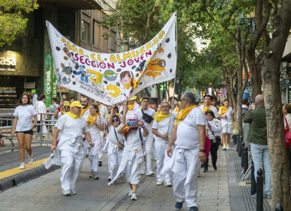 Evening procession through city streets by youth group organisation, Pilar 2025 festival event, Zaragoza, Aragon, Spain