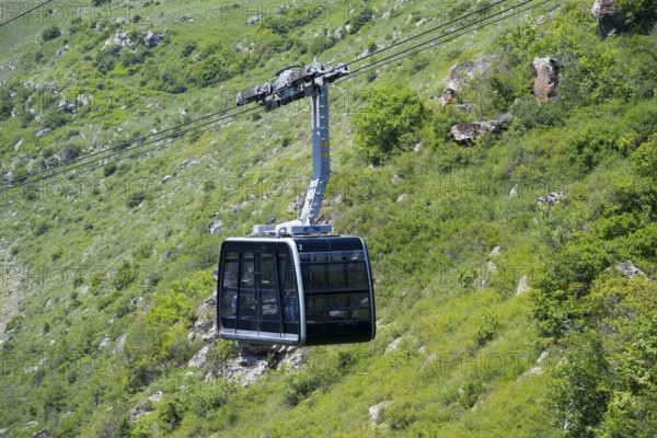 A cable car floats over green hilly terrain in a mountainous landscape, Tatev cable car, Wings of Tatev, Halidzor, Syunik province, Caucasus, Armenia