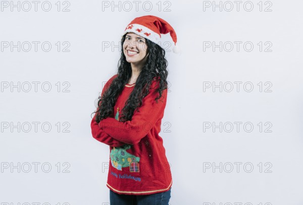 Smiling girl in Christmas hat with crossed arms. Portrait of smiling Latin girl in Christmas sweater with crossed arms, isolated