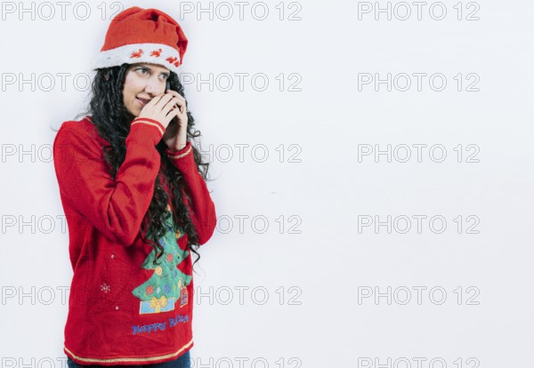 Woman in Christmas sweater secretly calling by phone. Girl in Christmas hat talking on the phone secretly