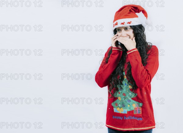 Girl in Christmas hat talking on the phone secretly. Woman in Christmas sweater secretly calling by phone