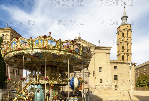 Funfair merry-go-round next to Church of San Juan de los Panetes with its Mudéjar tower, Zaragoza, Aragon, Spain