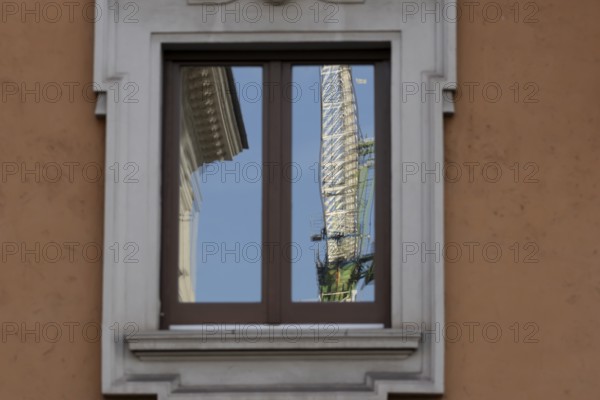 Window of a building with a reflection of a construction crane in the city of Rome, Italy