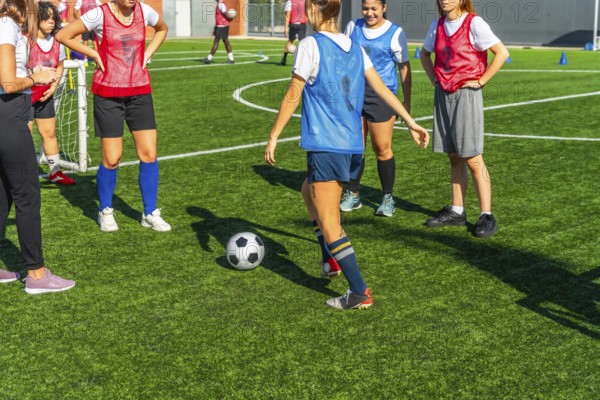 Diverse women soccer players training together on a sunny outdoor turf field, practicing dribbling, passing and teamwork to build fitness, skill and competitive confidence