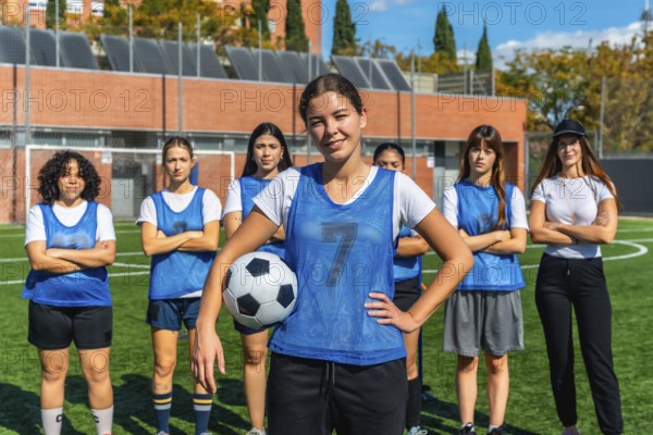 Confident young adult women soccer players standing together on the artificial grass football field, ready for training session, promoting female empowerment in sports