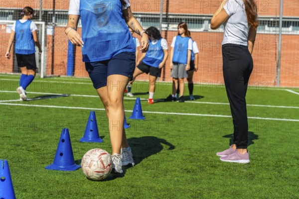 Young women's soccer team practicing dribbling drills with cones on green turf, focused and energetic during outdoor training session preparing for competition and improving skills