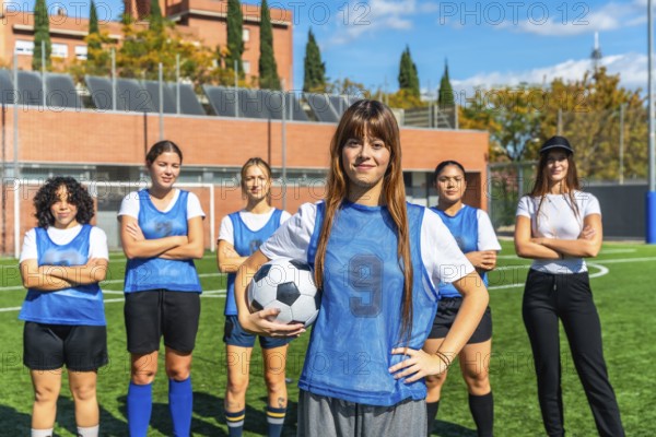 Diverse women's soccer team standing together on a sunny outdoor pitch, confident and ready to play, celebrating teamwork, empowerment and athleticism across generations and cultures
