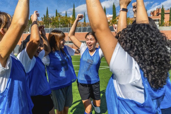 Women soccer players raise their arms and cheer in victory on a sunny outdoor field, celebrating teamwork, energy and empowerment after a winning match