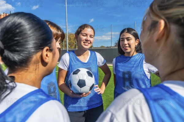 Women soccer players in blue uniforms huddled on a green field, smiling and planning strategy together before a game teamwork, focus, coaching and outdoor athletic preparation