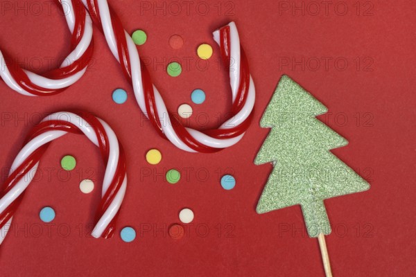 Candy canes and sugar confetti against red background, Christmas