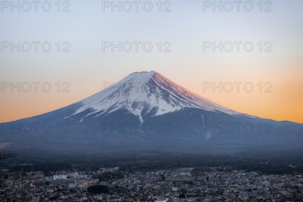 View of Mount Fuji volcano over Fujiyoshida City, at sunset, Yamanashi Prefecture, Japan