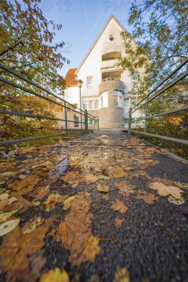 Autumn bridge with fallen leaves leading to a house, Aidlingen, Böblingen district, Germany