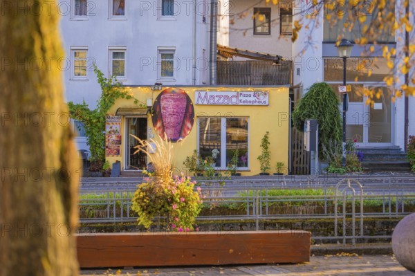 Yellow pizza building on a sunny street surrounded by autumn plants, Aidlingen, Böblingen district, Germany