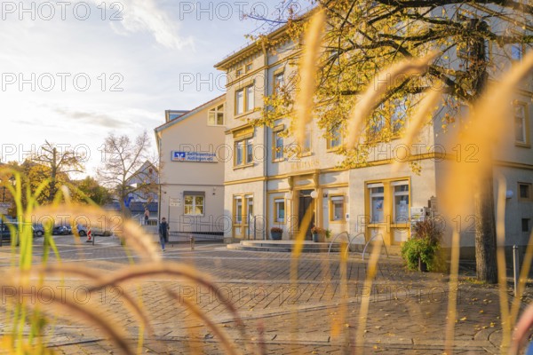 Village square in autumn sunlight with historic architecture in the background, Aidlingen, Böblingen district, Germany
