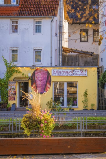 Small pizzeria with yellow façade in the midst of a colorful autumn backdrop, Aidlingen, Böblingen district, Germany
