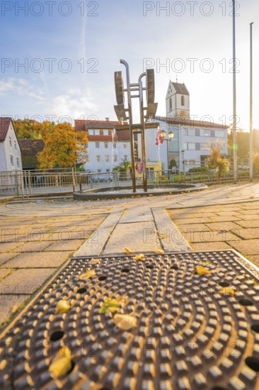 Urban scene in autumn with cobblestones, church in the background and sunny sky, Aidlingen, Böblingen district, Germany
