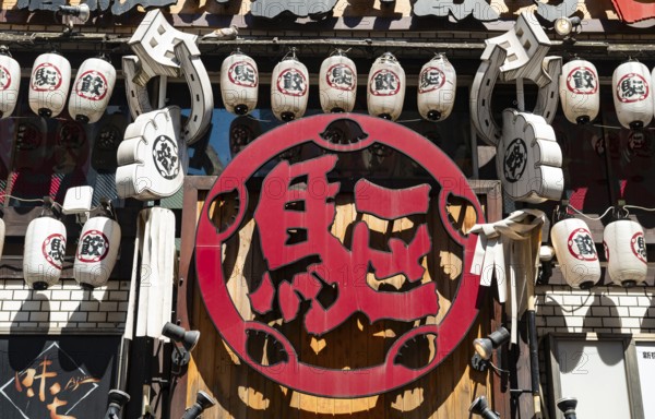 Red sign with Japanese characters, bar entrance decorated with lanterns, Shinjuku City, Tokyo, Japan