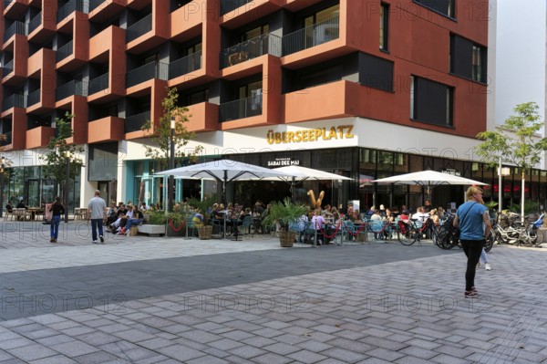 Street café with lettering Überseeplatz, passers-by, Westfield Überseequartier, modern shopping center, HafenCity, Hamburg, Germany