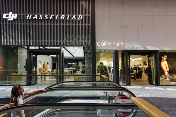 Shop window with logo, Hasselblad and Calvin Klein lettering, escalator, Westfield Überseequartier, modern shopping center, HafenCity, Hamburg, Germany