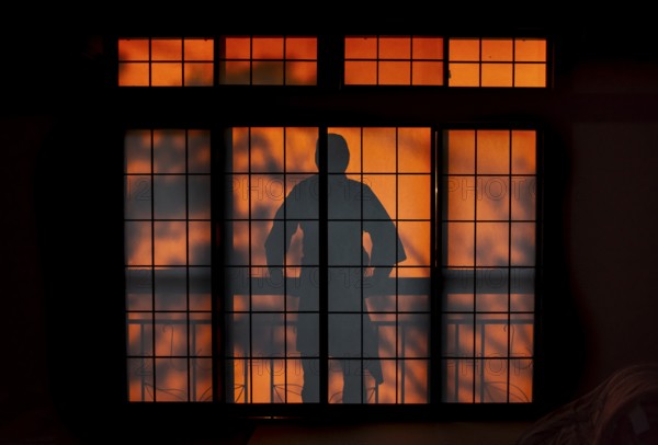 Shadows of a man on the balcony behind a sliding shoji door in a traditional Japanese house, Yamanouchi, Nagano, Japan