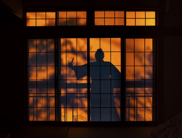 Shadow of a woman, burglar with knife, assassin, ninja, on the balcony behind a sliding shoji door in a traditional Japanese house, Yamanouchi, Nagano, Japan